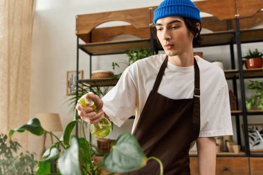 Genç bir adam tutkusunu yansıtan yeşil, sıcacık bir stüdyoda çiçeklerini suluyor..