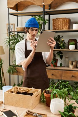 İyi aydınlatılmış bir stüdyoda bitkilerle ilgilenen yakışıklı genç adam görevine odaklanmış ve tablet kullanıyordu..