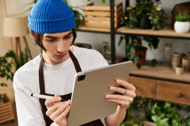 Genç adam bitkileri nakletmeye ve canlı bir stüdyoda rehberlik için bir tablet kullanmaya odaklanmış..