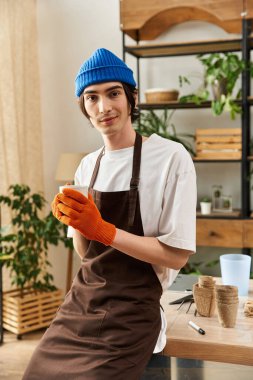 Rahat bir stüdyoda genç bir adam eldiven giyerken bitki nakli yapmaktan zevk alıyor..