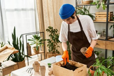Yakışıklı bir genç adam dikkatle yeşillik dolu samimi bir stüdyoya fidanlar ekiyor..