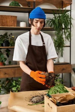 Eldivenli genç adam, doğayla çevrili şık bir çalışma alanına canlı bitkiler naklediyor..