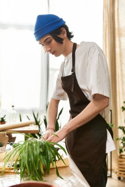 Genç bir adam, parlak bir stüdyoda yemyeşil bitkileri dikkatlice naklederken dikkatle odaklanır..