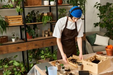 Yakışıklı genç adam sanatsal bir stüdyo ortamında toprak ve bitkilerle özenle çalışıyor..