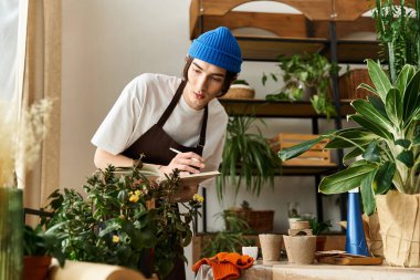 Genç adam canlı stüdyo ortamında çeşitli bitkiler naklediyor, not alın..