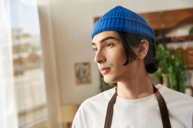 Güneşli bir stüdyoda, yemyeşil bitkilerin arasında, odaklanmış ve özenli bir genç adam..