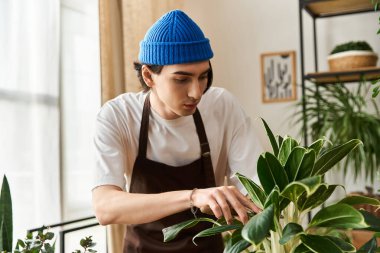 Mavi bereli genç bir adam şık bir stüdyoda çiçeklerle ilgilenir ve görevine odaklanır..