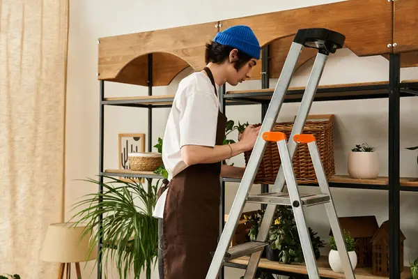 Mavi bereli genç bir adam şık iç mekânında bitki nakletmeye odaklanıyor..