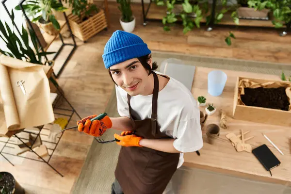 Stüdyodaki genç adam bahçe işleriyle uğraşırken mutlu bir şekilde bitki naklediyor..