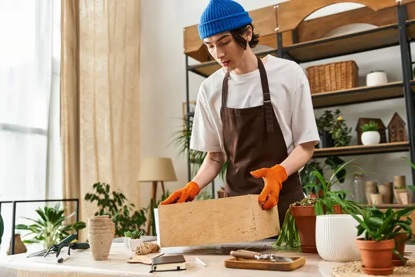 Yakışıklı genç adam dikkatlice yeşillik naklediyor, canlı bitkiler ve aletlerle çevrili..