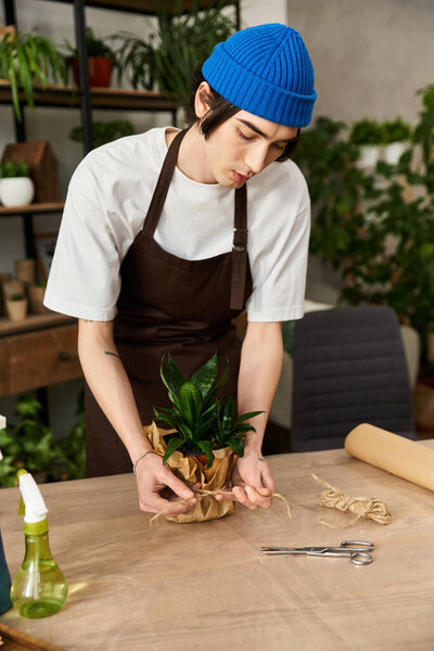 A young, handsome man carefully transplanting plants in a creative studio filled with greenery.