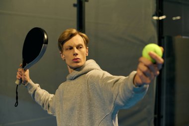 Odaklanmış genç bir adam kapalı alanda oynanan bir oyun sırasında topu iade etmeye hazırlanıyor..