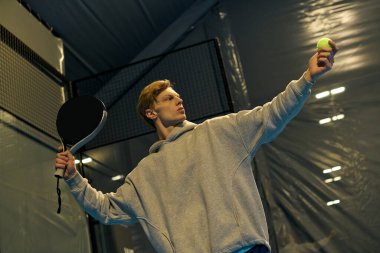 Dinamik genç sporcu Padel oynarken odaklanma ve kararlılıkla hizmet etmeye hazırlanıyor.