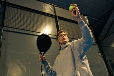 Odaklanmış genç bir atlet topu kaldırıyor, kapalı sahada servis yapmaya hazır..