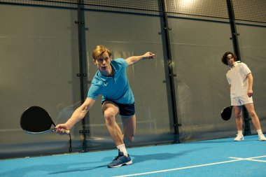 İki genç erkek oyuncu heyecan verici bir Padel maçında yeteneklerini sergiliyorlar..