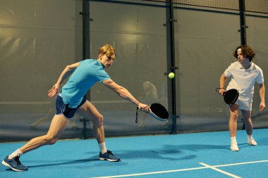 İki genç sporcu sahada yeteneklerini sergileyerek heyecan verici bir Padel maçına çıkıyorlar..