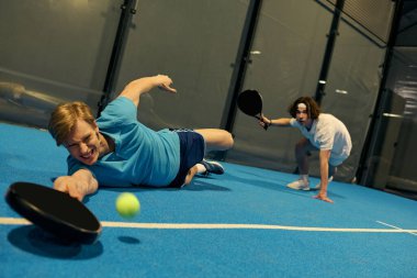 Genç sporcular Padel oynarken, sahada topa atlarken azim ve beceri gösteriyorlar..