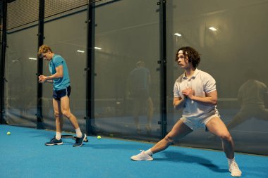 Yetenekli sporcular, enerjik bir Padel oturumunda beceri geliştirmeye odaklanırlar..