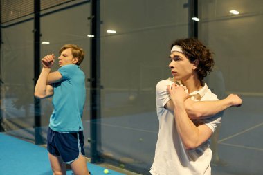 Padel kortunda ısınan iki genç adam bugünkü maça hazırlanıyor..