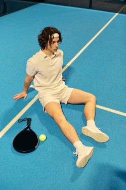 Genç bir sporcu heyecanlı bir maçtan sonra mavi padel sahasında mola veriyor..