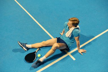 Sporcu, maça yansıyan mavi padel sahasında otururken nefes alıyor..