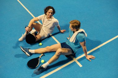 İki genç sporcu, heyecan verici bir miting sonrası stratejilerini tartışıyorlar..