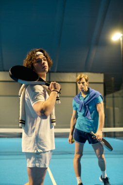 İki genç sporcu parlak ışıkların altında padel yeteneklerini sergiliyorlar..