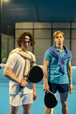 İki genç erkek sporcu canlı bir kortta heyecanlı bir Padel maçına hazırlanıyor..