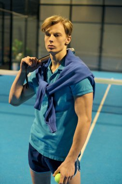 Odaklanmış genç bir oyuncu atletizm becerilerini geliştirmek için Padel kortunda kendinden emin bir şekilde duruyor.