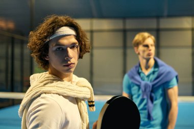 İki genç adam şık spor kıyafetleriyle Padel kortunda enerjik bir şekilde yarışıyor..