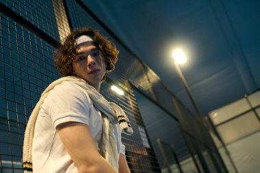 Spor kıyafetleri giymiş genç bir adam Padel maçına hazırlanıyor, odaklanmış ve kararlı..