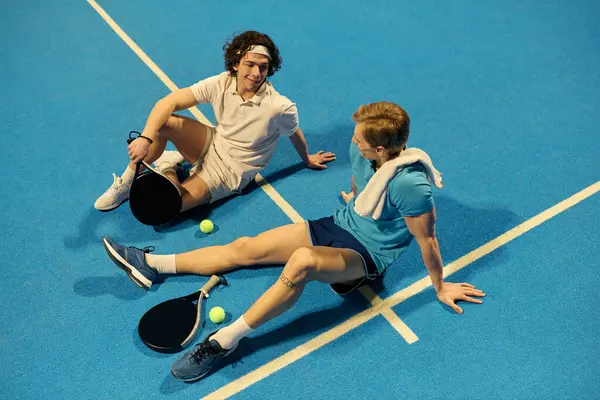 İki genç sporcu, heyecan verici bir miting sonrası stratejilerini tartışıyorlar..