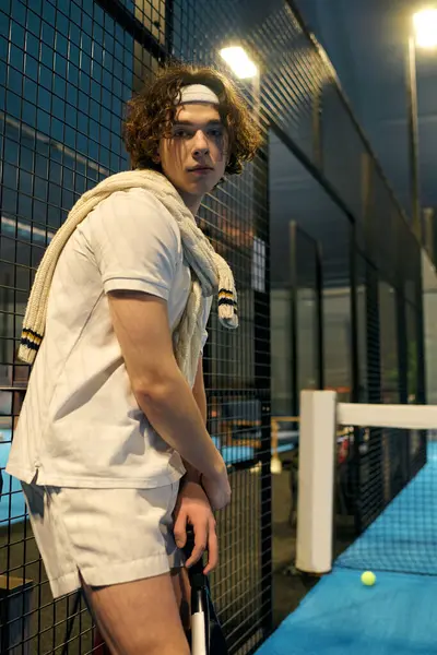 Atletik giyimli genç bir adam Padel oynamaya hazırlanıyor. Konsantrasyon ve atletizm gösteriyor..