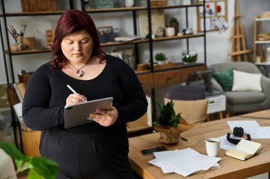 Yaratıcı kadın, resim atölyesindeki bir tablete çizimler yapıyor. Etrafı malzemelerle çevrili..