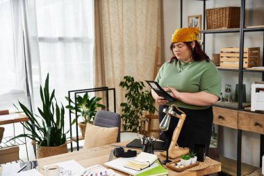 Düşünceli bir kadın bir sanat stüdyosunda duruyor, malzemelerle çevrili ve yaratıcılığa dalmış..