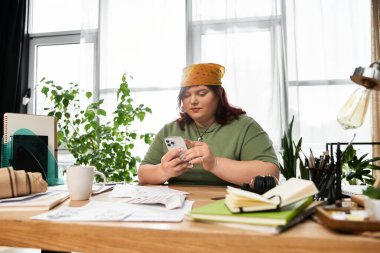 Şık bir kadın, canlı bir sanat stüdyosunda telefonuyla yaratıcılığını keşfediyor..