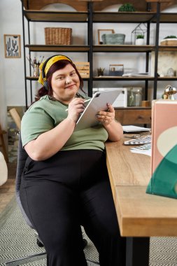 Parlak bir sanat stüdyosunda, güzel bir kadın yaratıcılığını sergileyerek bir tablete neşe içinde eskizler..