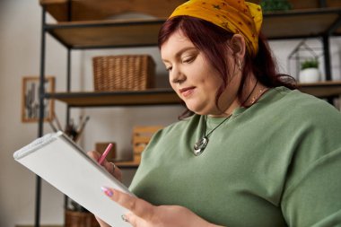 Şık bir sanat stüdyosundaki yaratıcı kadın dikkatli bir gözle ve odaklanmış bir ifadeyle fikirler çiziyor.