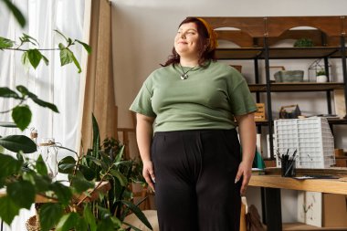 Güzel bir kadın canlı bitkiler ve yaratıcı aletlerle çevrili bir sanat stüdyosunda güvenle duruyor..