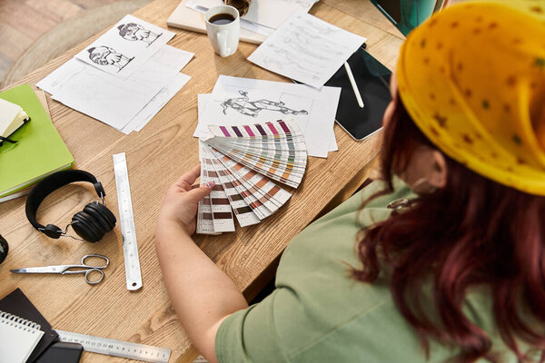 A woman examines color swatches at her art studio, surrounded by projects.