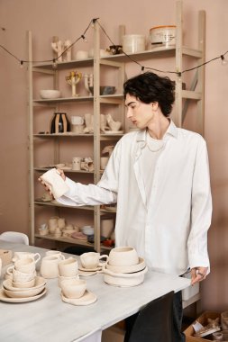 Tarz sahibi adam seramik yapar, güzel çömlek tasarımları ve sanatsal aletlerle çevrili..