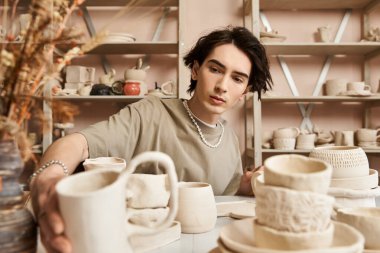 Yaratıcı bir genç adam çömlek atölyesinde güzel çömlek parçaları yapmaya odaklanmış..