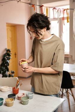 Canlı bir stüdyoda sanatsal enerjiyle dolu bir çömlek işine dalmış şık bir adam..