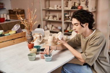 Şık bir adam çömlekçilik sanatıyla ilgileniyor, yaratıcı bir stüdyoda eşsiz parçalar yapıyor..