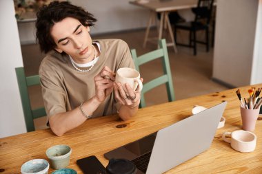 Şık bir adam çömlek atölyesinde kil şekillendirir ve beyin fırtınası yapar..