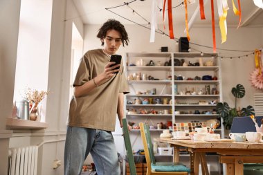 Genç bir adam yaratıcılığını seramik dolu bir sanat stüdyosunda sergiliyor..