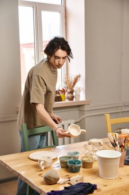 Sanat enerjisiyle dolu yaratıcı bir çömlek atölyesinde seramik şekillendirmeye odaklanmış bir adam..