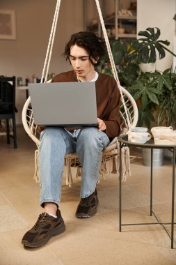 Yakışıklı bir adam yeşilliklerle çevrili bir çömlek atölyesinde sanatsal işler yapıyor..