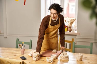 Yakışıklı bir adam, canlı bir stüdyo ortamında killeri şekillendirerek çömlek sanatıyla ilgileniyor..