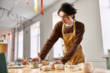 Şık bir adam sanatsal aletlerle dolu yaratıcı bir stüdyoda ustalıkla çömlek şekillendiriyor..
